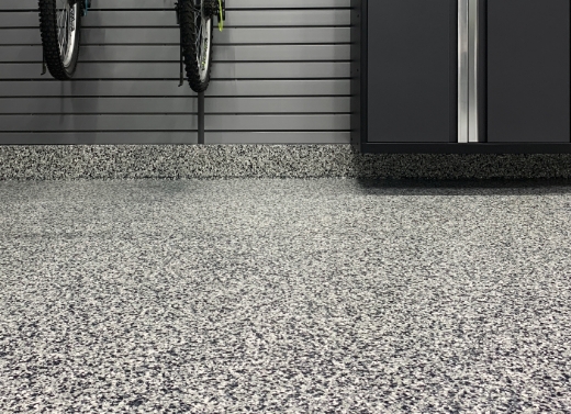 A garage showcasing a bike rack and a bike on the floor, enhanced by Polyaspartic Garage Flooring.